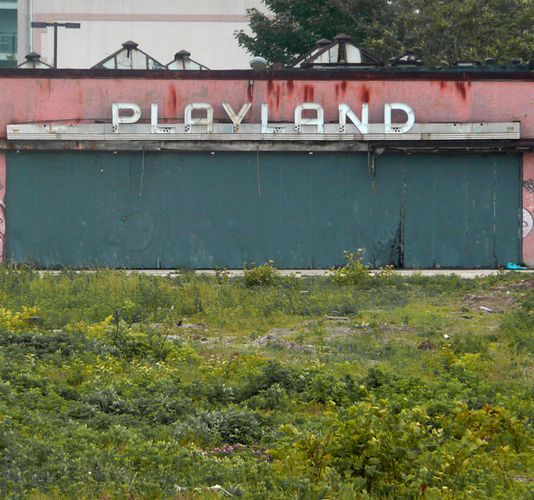 An old arcade stares out across a vacant lot.