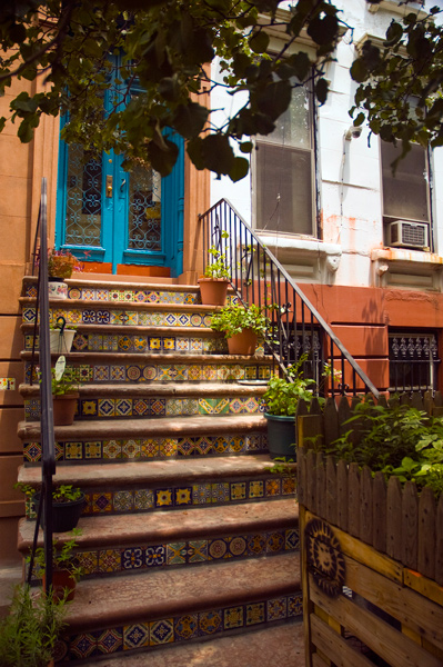 The steps leading up to the entrance of a home are decorated with a wide variety of multi-colored tiles.
