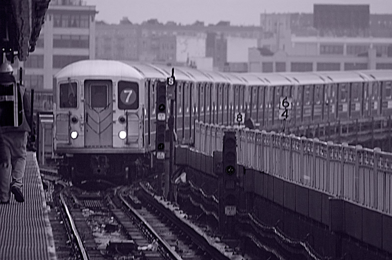 A subway train pulls into an elevated station, on a curved track.