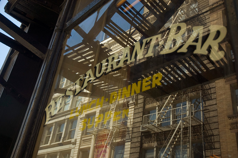 Fire escapes are reflected in the glass window of a restaurant.