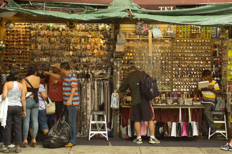 Shoppers review accessories at an open air store.