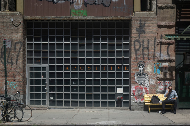 A man on a bench, next to a large window laid out in a grid.