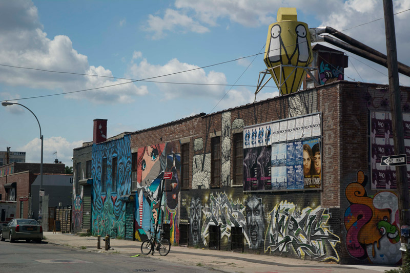 Several buildings on a block, decorated with street art.