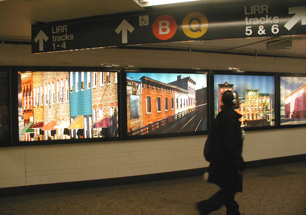 Man walking by backlit photographs.